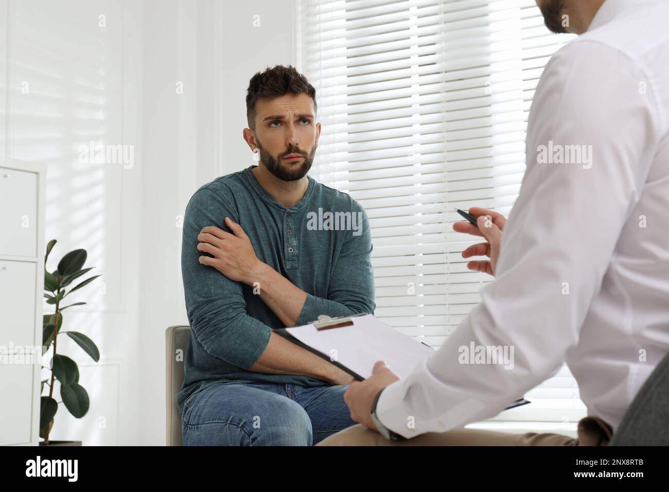 Psicoterapeuta che lavora con l'uomo tossicodipendente al chiuso Foto Stock