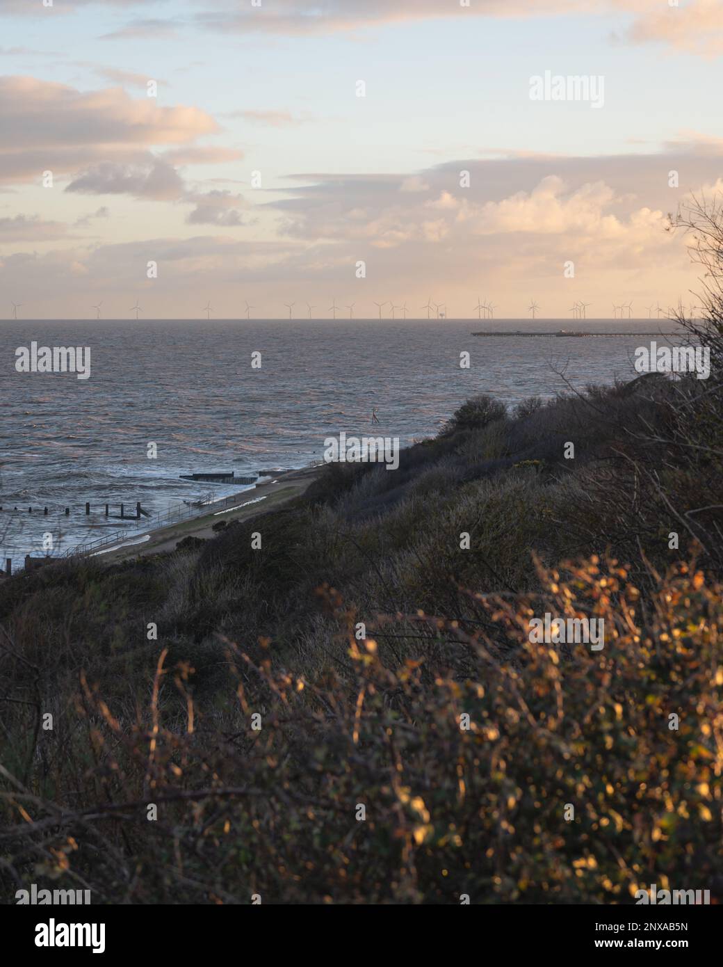 Walton al tramonto di Naze. Vista sugli interruttori a onde. Toni caldi del sole. Le onde si schiantano. Giorno ventoso. Foto Stock