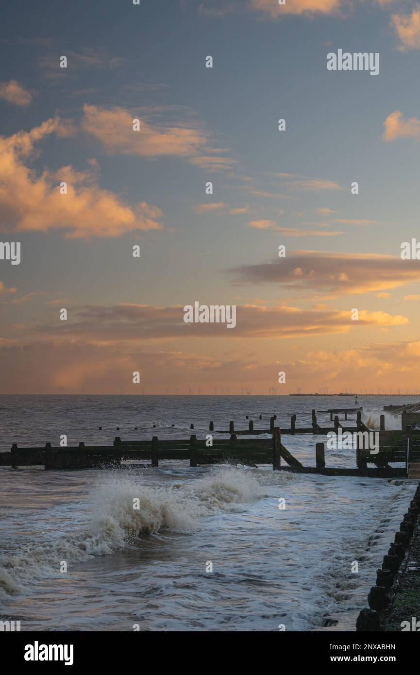 Walton al tramonto di Naze. Vista sugli interruttori a onde. Toni caldi del sole. Le onde si schiantano. Giorno ventoso. Foto Stock