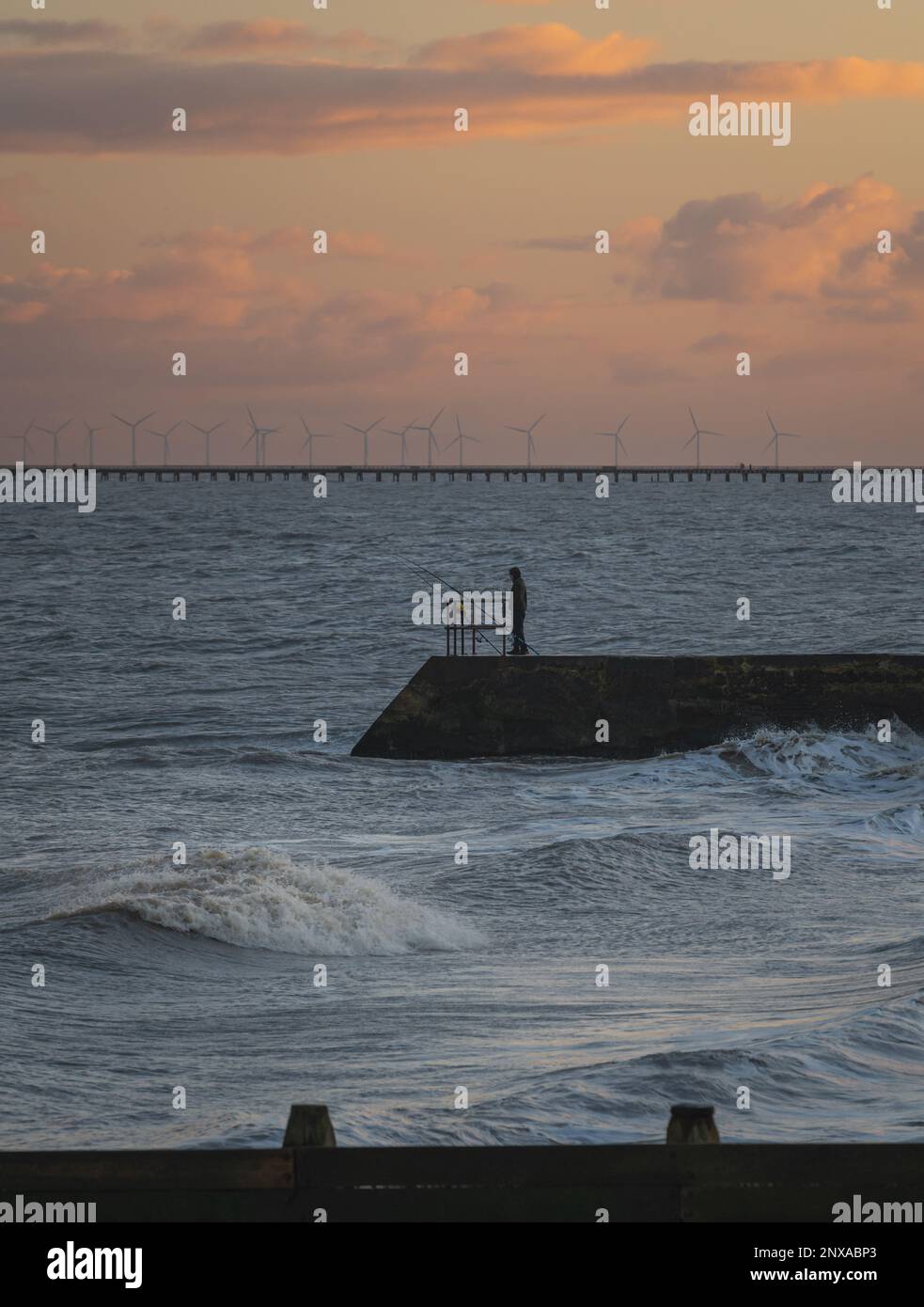 Walton al tramonto di Naze. Vista sugli interruttori a onde. Toni caldi del sole. Le onde si schiantano. Giorno ventoso. Foto Stock
