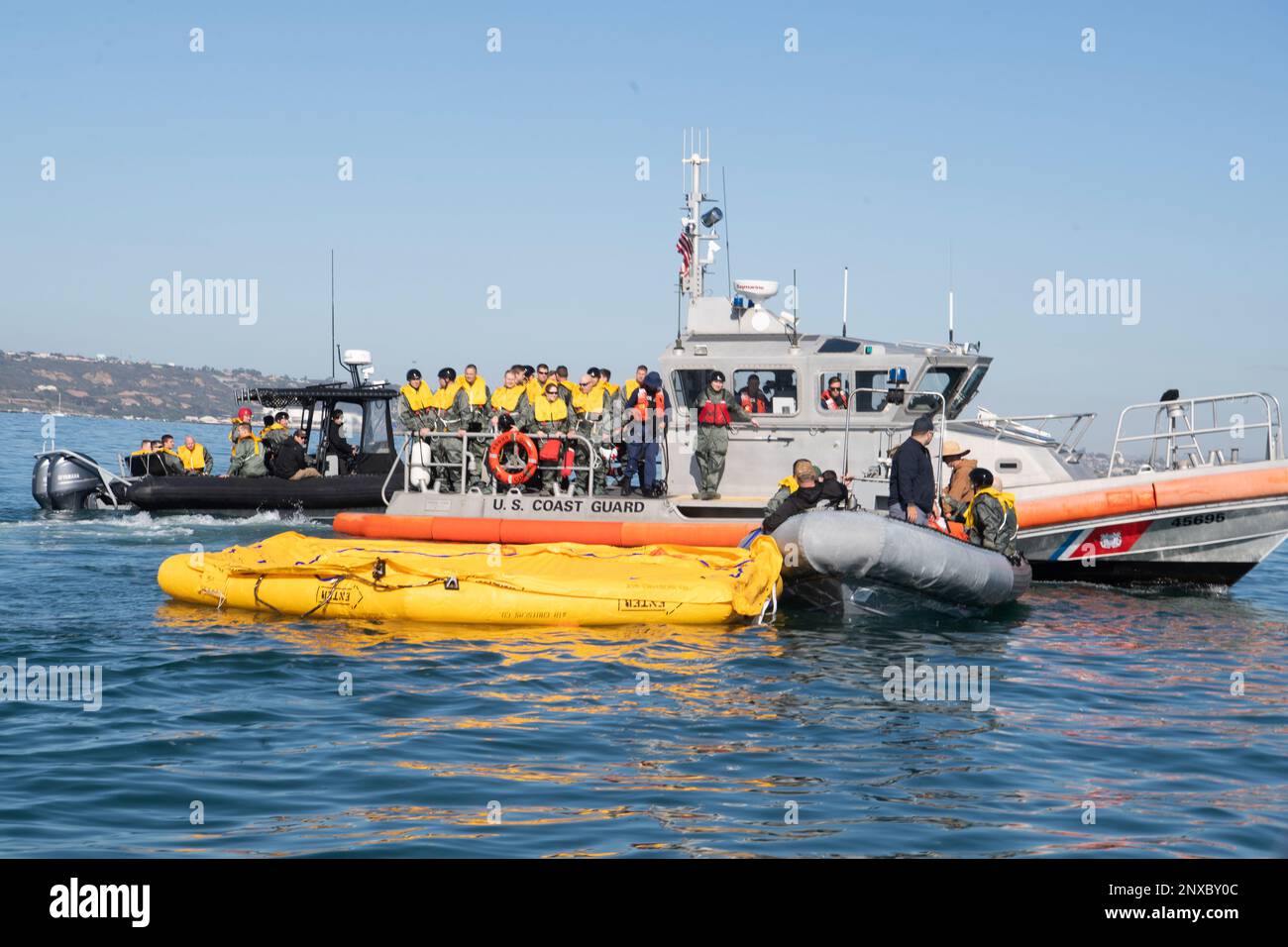 230119-N-LR048-1088 SAN DIEGO (19 gennaio 2023) – i marinai della Marina assegnati a Helicopter Sea Combat Squadron (HSC) 3 (davanti), schierano una zattera di vita da 46 uomini mentre i membri dell'equipaggio assegnati a Air Force 445th Airlift Wing si preparano a sbarcare da un US Guardia costiera (USCG) nave (indietro), assegnato al settore della Guardia costiera San Diego durante un incidente di massa in mare di recupero del personale evento al largo della costa della California meridionale, 19 gennaio. Durante l'evoluzione, HSC-3 Chief of Naval Operations Search and Rescue Model Manager ha supervisionato l'esercizio di Ricerca e salvataggio con HSC-8, HSC-23, Coast Guard Sector San Diego e Crewmemb Foto Stock