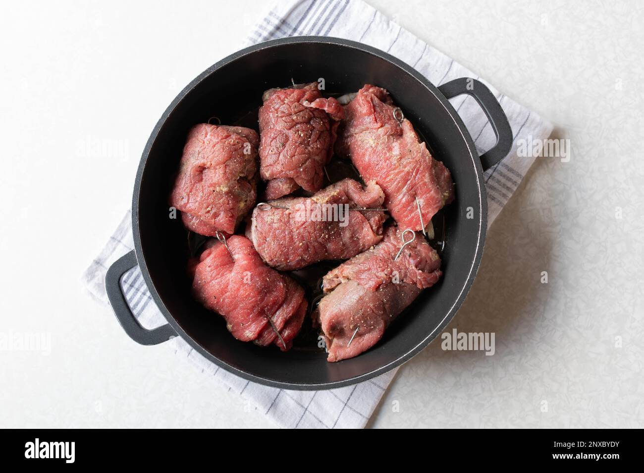 Involtini di manzo con ripieno, crudo e crudo in una pentola di tostatura. Pronto per cucinare preparazione, cottura, preparazione. Parte di una serie. Foto Stock