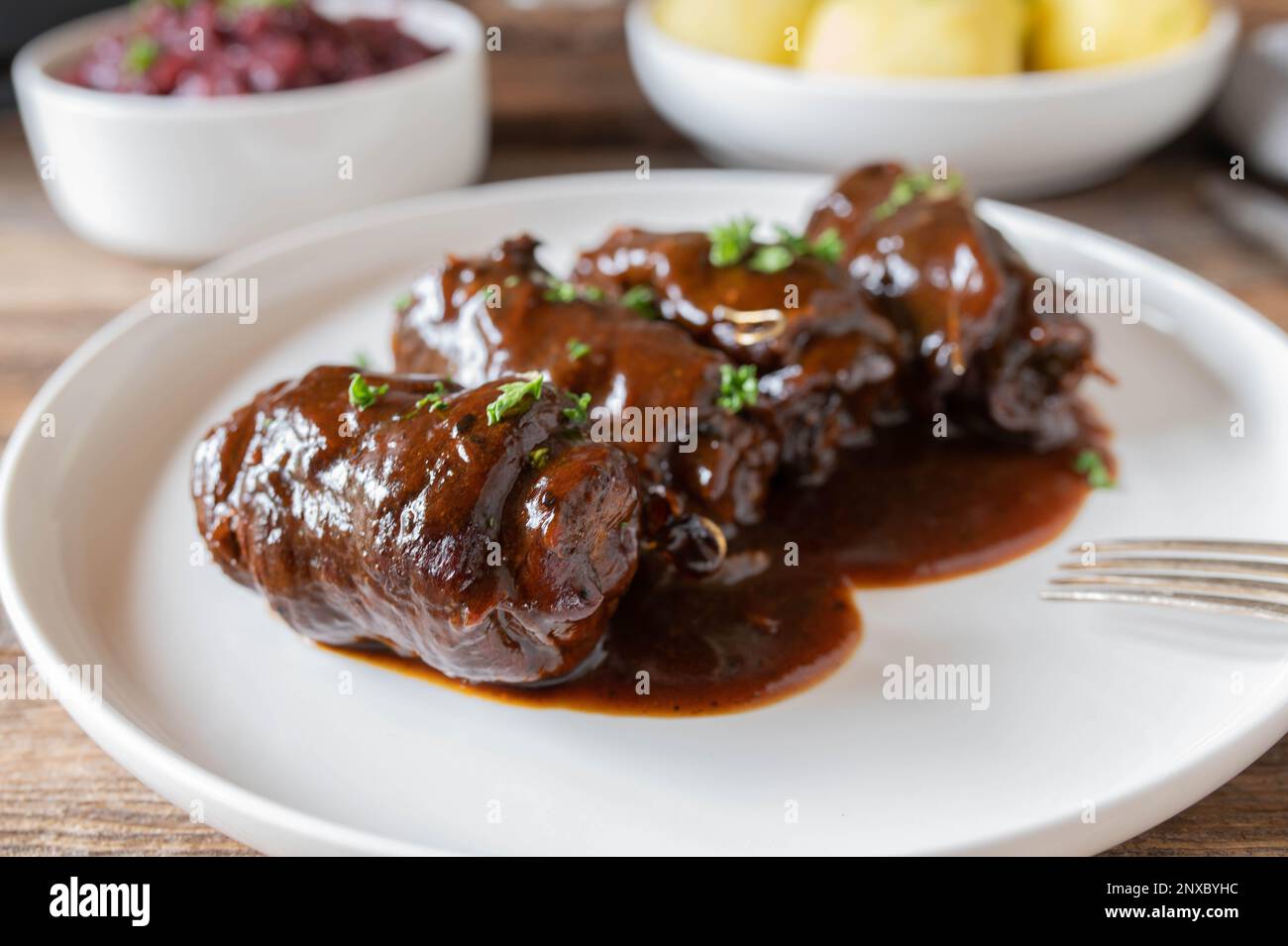 Involtini di manzo con delizioso sugo di carne. Piatto di carne tradizionale tedesco con cavolo rosso e gnocchi di patate Foto Stock