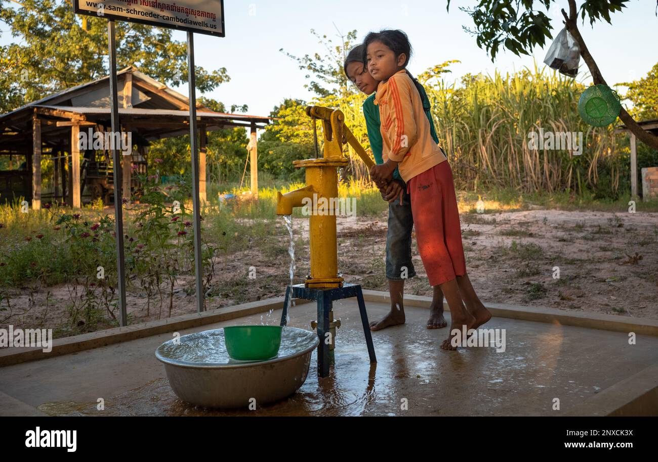 Due giovani ragazze in un villaggio nella provincia rurale di Siem Reap in Cambogia, lavorano insieme per pompare l'acqua da una pompa di acqua di metallo tradizionale che era stato fatto Foto Stock