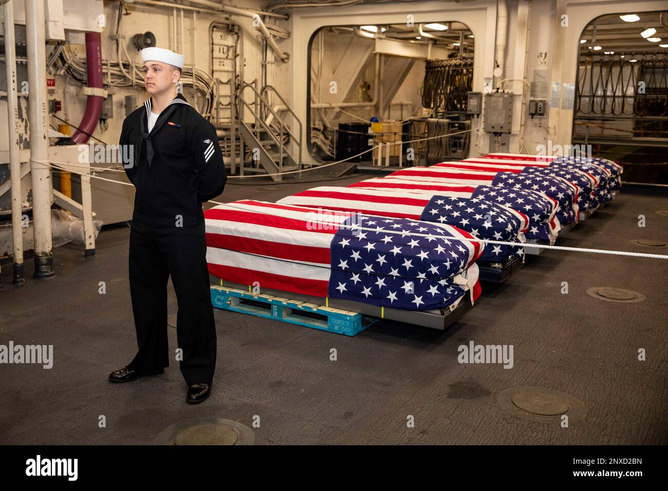 Il tecnico del sistema informativo Seaman Joshua French, assegnato alla nave portuale di trasporto anfibio di classe San Antonio USS Arlington (LPD 24), si trova a sorvegliare le casse in scena a bordo di Arlington in preparazione di una sepoltura in mare, il 21 febbraio 2023. La Marina esegue sepolture in mare per una media di 1.500 resti cremati e 15 resti caduti all'anno. Foto Stock