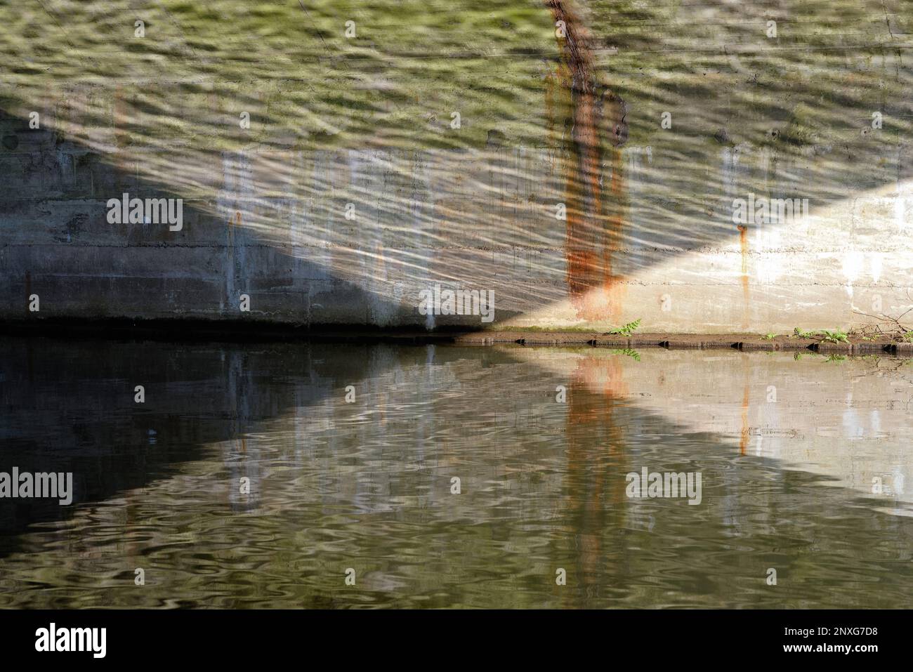 Forme triangolari astratte formate da riflessi sulla superficie dell'acqua e arco di ponte in pietra Foto Stock