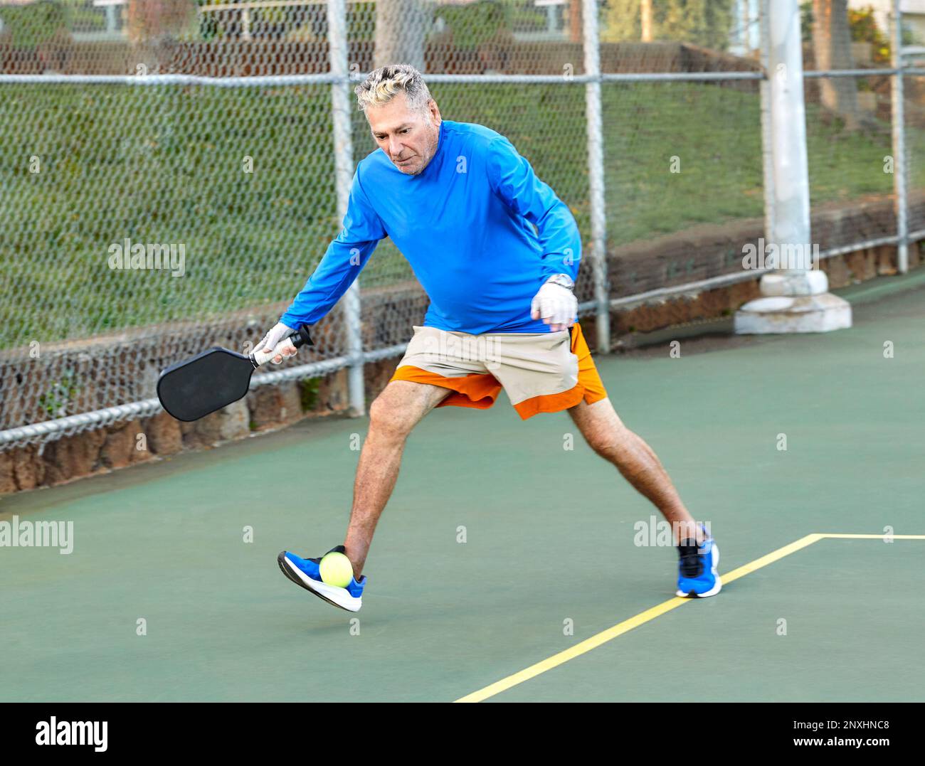 Uomo anziano attivo che gioca a Pickle Ball all'aperto Foto Stock
