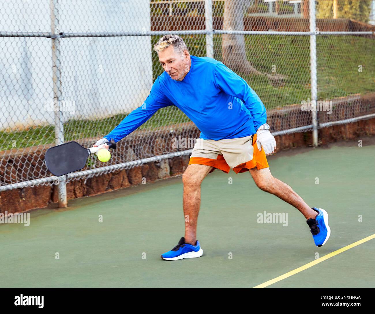 Uomo anziano attivo che gioca a Pickle Ball all'aperto Foto Stock