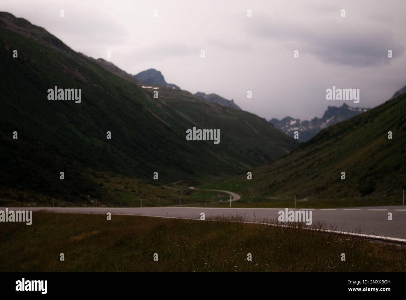 Strada in montagne verdi in tempo nuvoloso nelle Alpi Foto Stock