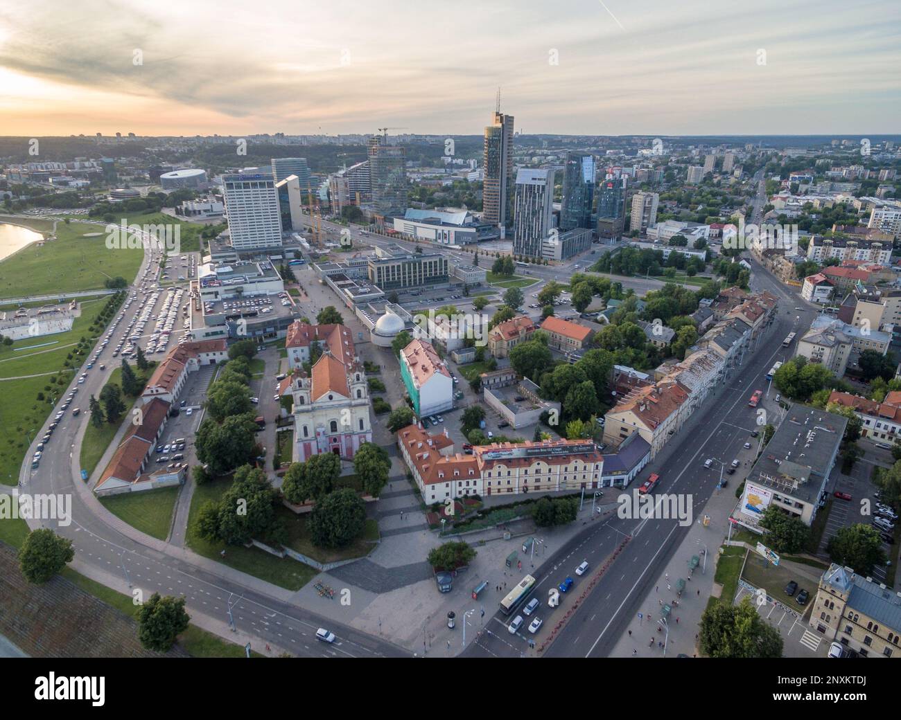 Il paesaggio urbano di Vilnius con il quartiere degli affari. Tramonto cielo. Chiesa di San Arcangelo Raffaello in primo piano Foto Stock
