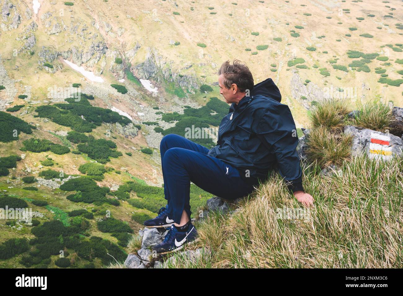 Un uomo si siede e gode della splendida vista dell'ambiente montagnoso dei Bassi Tatra, Brezno, Slovacchia Foto Stock