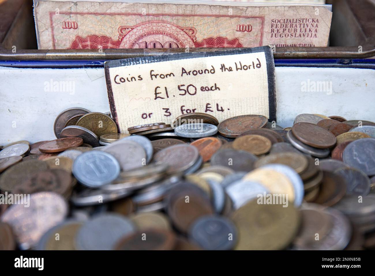 Monete da tutto il mondo. Valuta estera in vendita su Portobello Road nel quartiere di Notting Hill, Londra, Inghilterra. Foto Stock