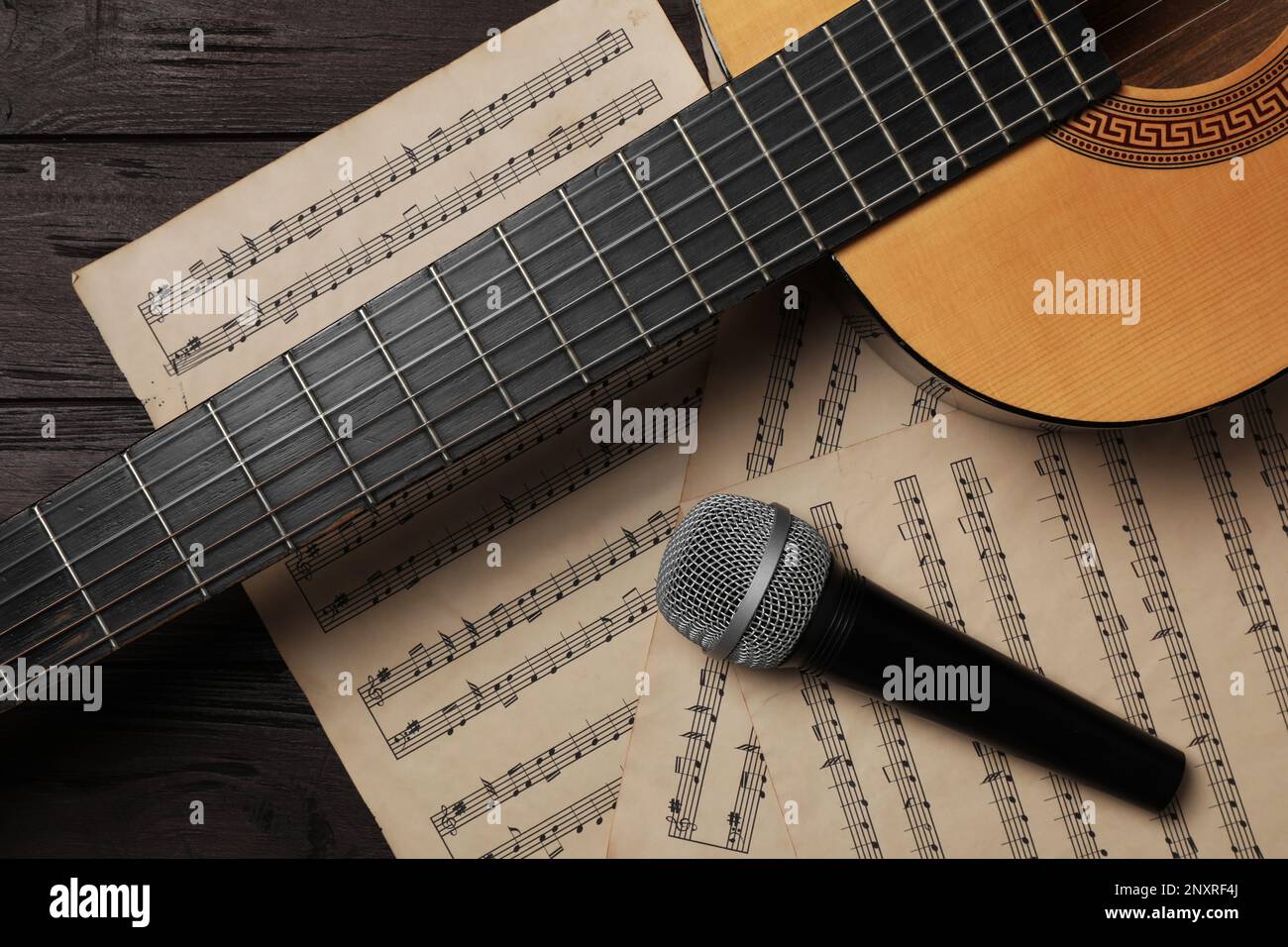 Composizione con chitarra e note musicali su tavolo in legno, piatto Foto Stock