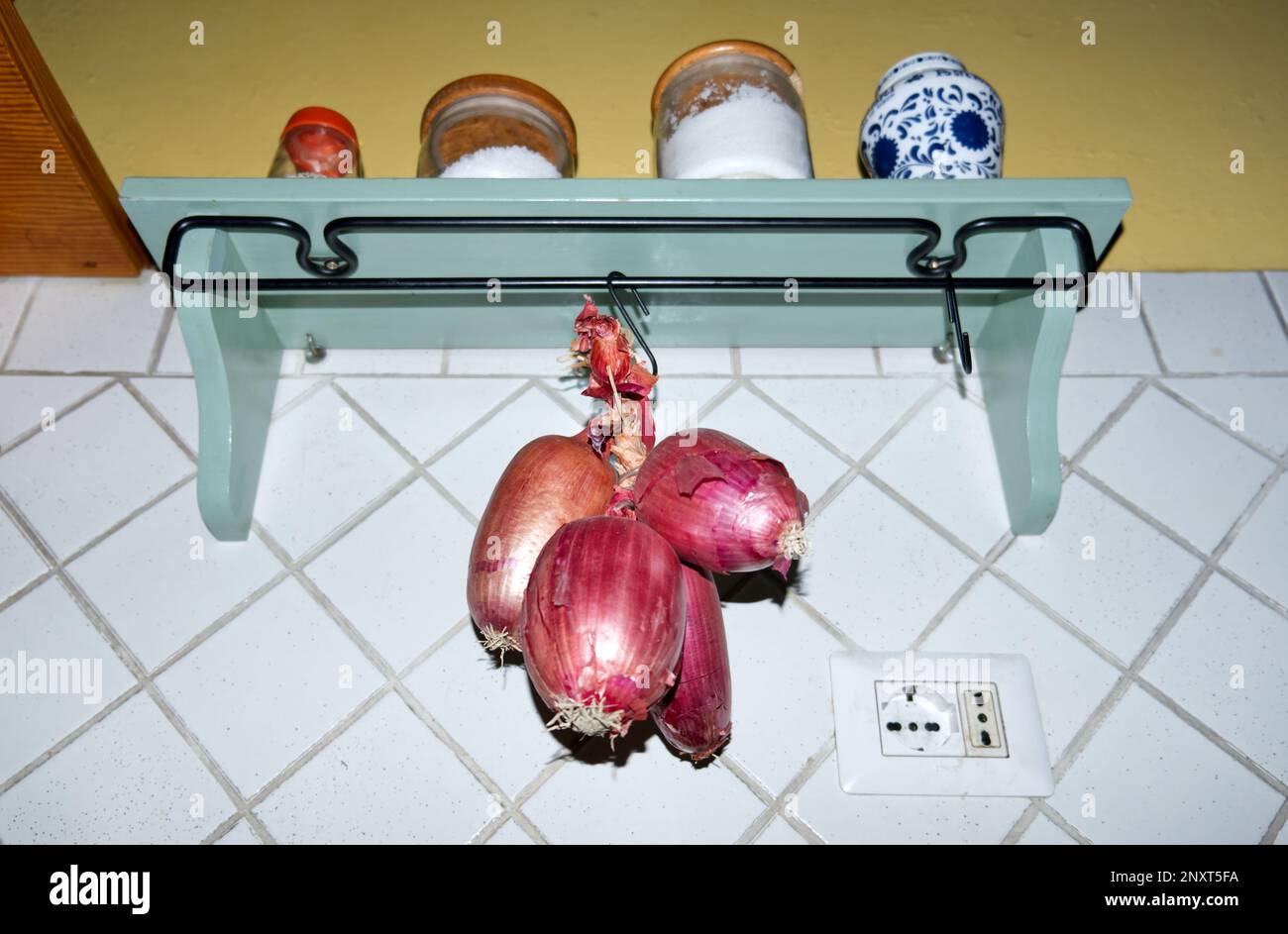 Cucina italiana: Una treccia di cipolline rosse dolci tropea appese in cucina Foto Stock