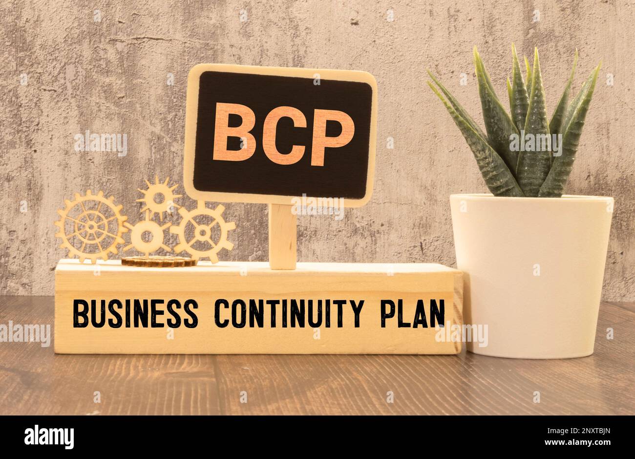 Su un tavolo da ufficio di colore chiaro si trova un computer, una calcolatrice nera, una penna e un notebook con il testo BCP Business Continuity Plan Foto Stock