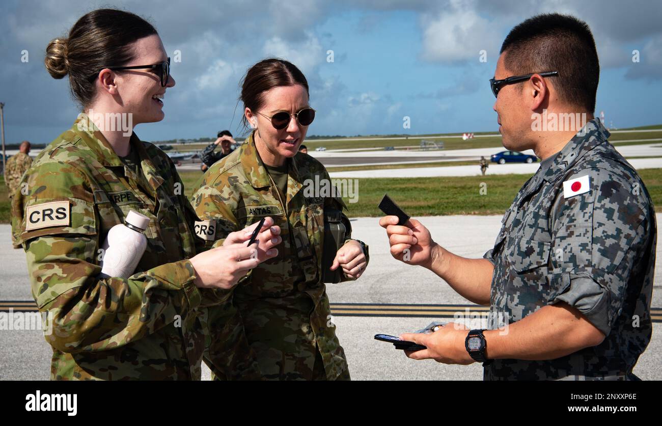 I membri della Royal Australian Air Force e un membro della Japan Air Self-Defense Force tratteranno delle patch durante l'esercitazione statica di Cope North 23 presso la base dell'aeronautica militare Andersen, Guam, 8 febbraio 2023. CN23 è un ente multilaterale statunitense L'esercitazione di formazione sul campo sponsorizzata dalle forze aeree del Pacifico si è focalizzata sull'integrazione aerea trilaterale per l'occupazione di grandi forze, l'occupazione agile in combattimento, l'assistenza umanitaria e la formazione in caso di disastri. Foto Stock