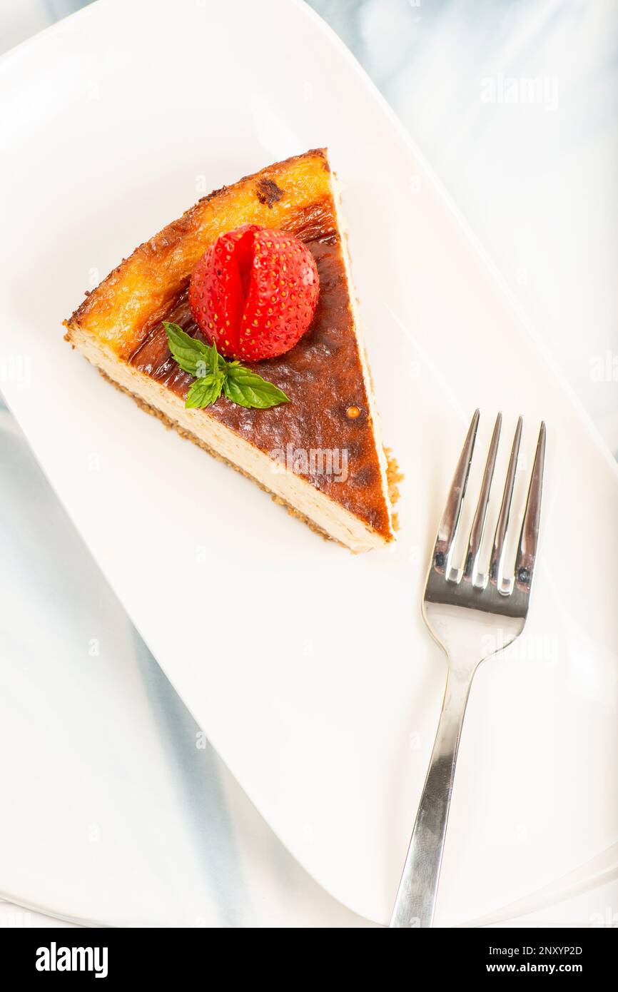 Cheesecake di New York cremoso con fiori freschi, foglie di menta e fragole. Foto Stock