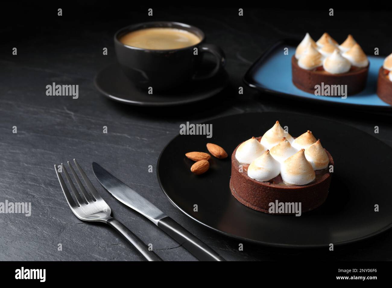 Deliziosa crostata di cioccolato al caramello salato con meringa e mandorle su tavola nera Foto Stock
