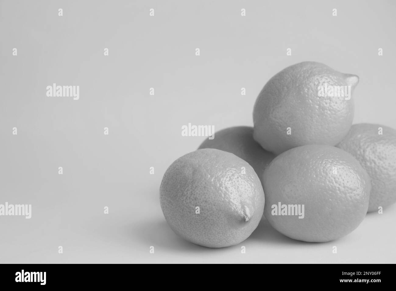 Limoni freschi maturi su sfondo grigio, spazio per il testo. Tono bianco e nero Foto Stock