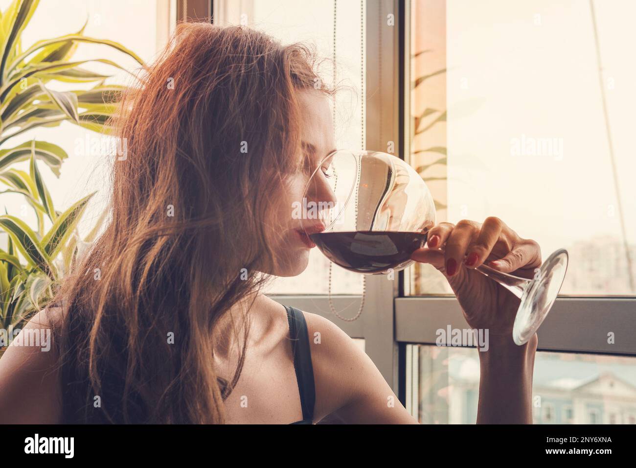 Closeup Ritratto di giovane donna cliente di bere il vino rosso con gli occhi chiusi. Donna di bere vino, prendendo un sorso di un bicchiere di vetro. Degustazione di vino a th Foto Stock
