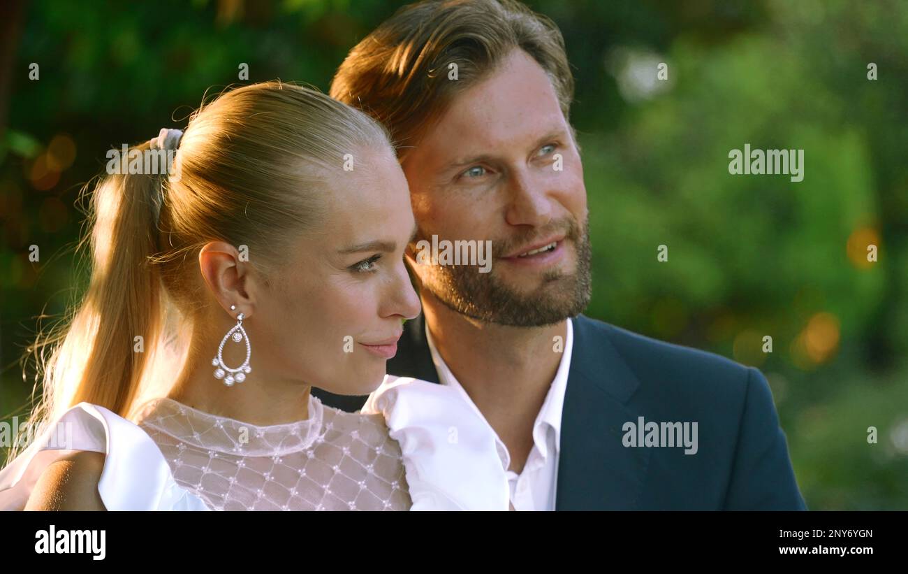 Bella sposa con lo sposo in un parco cittadino su uno sfondo verde sfocato. Azione. Uomo e donna sposi novelli durante le riprese video all'aperto Foto Stock