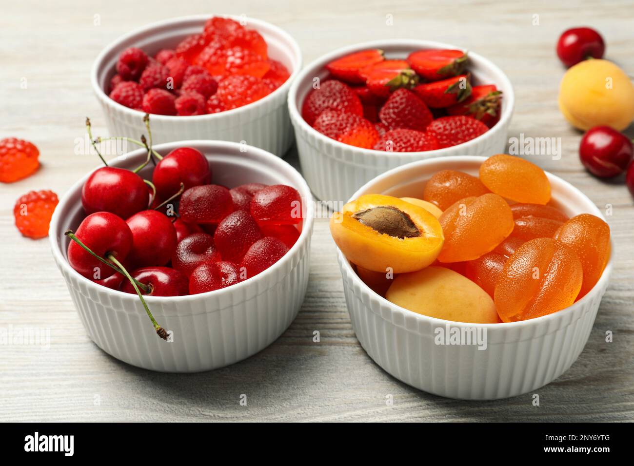 Deliziose caramelle gommose e frutta fresca su tavola di legno bianco Foto Stock