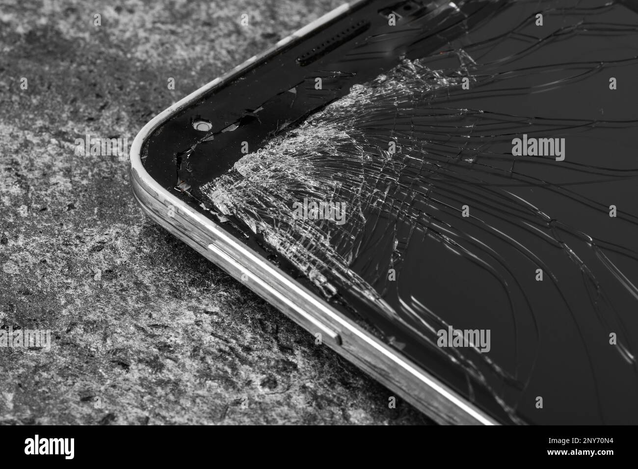 Smartphone con schermo incrinato su sfondo di pietra grigia, primo piano. Riparazione del dispositivo Foto Stock