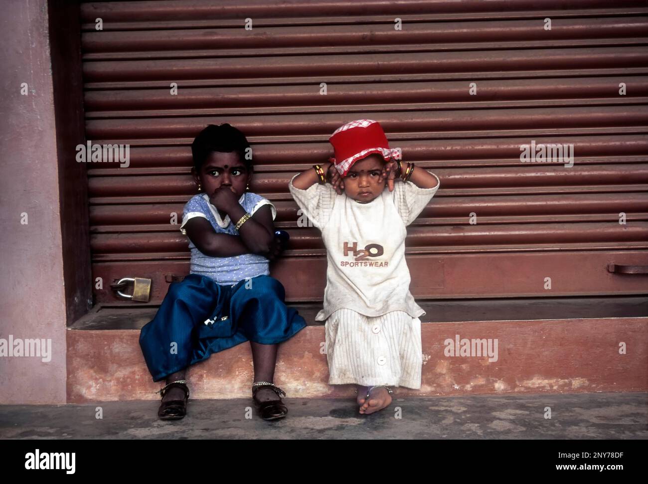 I bambini sono seduti davanti al negozio chiuso, Kerala, India Foto Stock