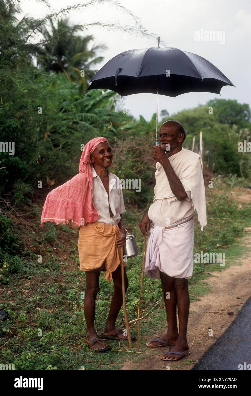 Due villaggio uomo che parla di agricoltura durante una stagione di pioggia Tamil Nadu, India Foto Stock