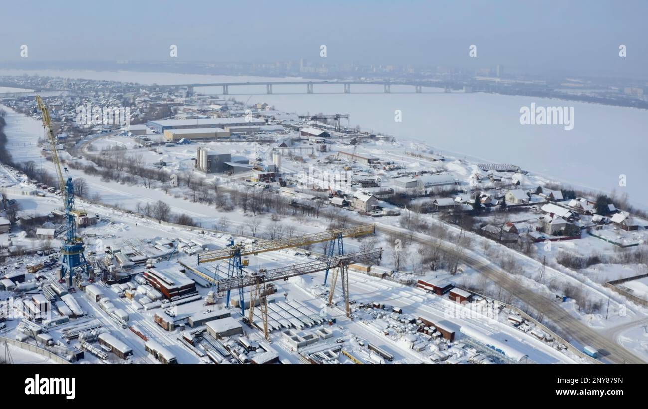 Veduta aerea di una città situata vicino al lago in una foschia mattutina. Fermo. Villaggio coperto di neve, fiume congelato Foto Stock