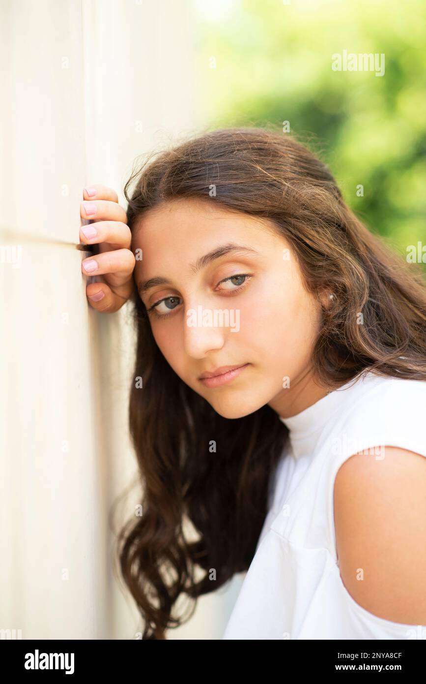 Triste teenagegirl appoggiato contro il muro guardando lontano all'aperto Foto Stock