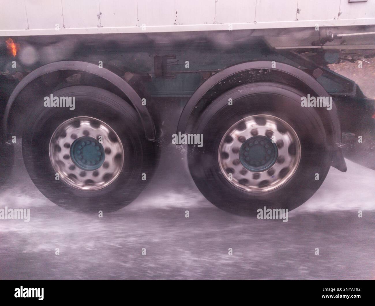 Le ruote dei camion spruzzano acqua sulla strada. Concetto di guida in caso di maltempo. Foto Stock