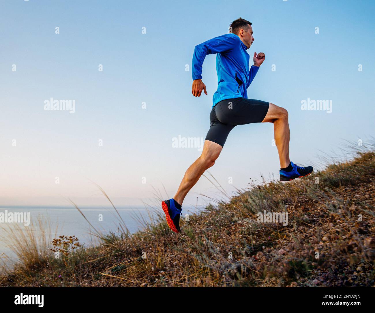 corridore maschio che corre in salita in background cielo e mare Foto Stock