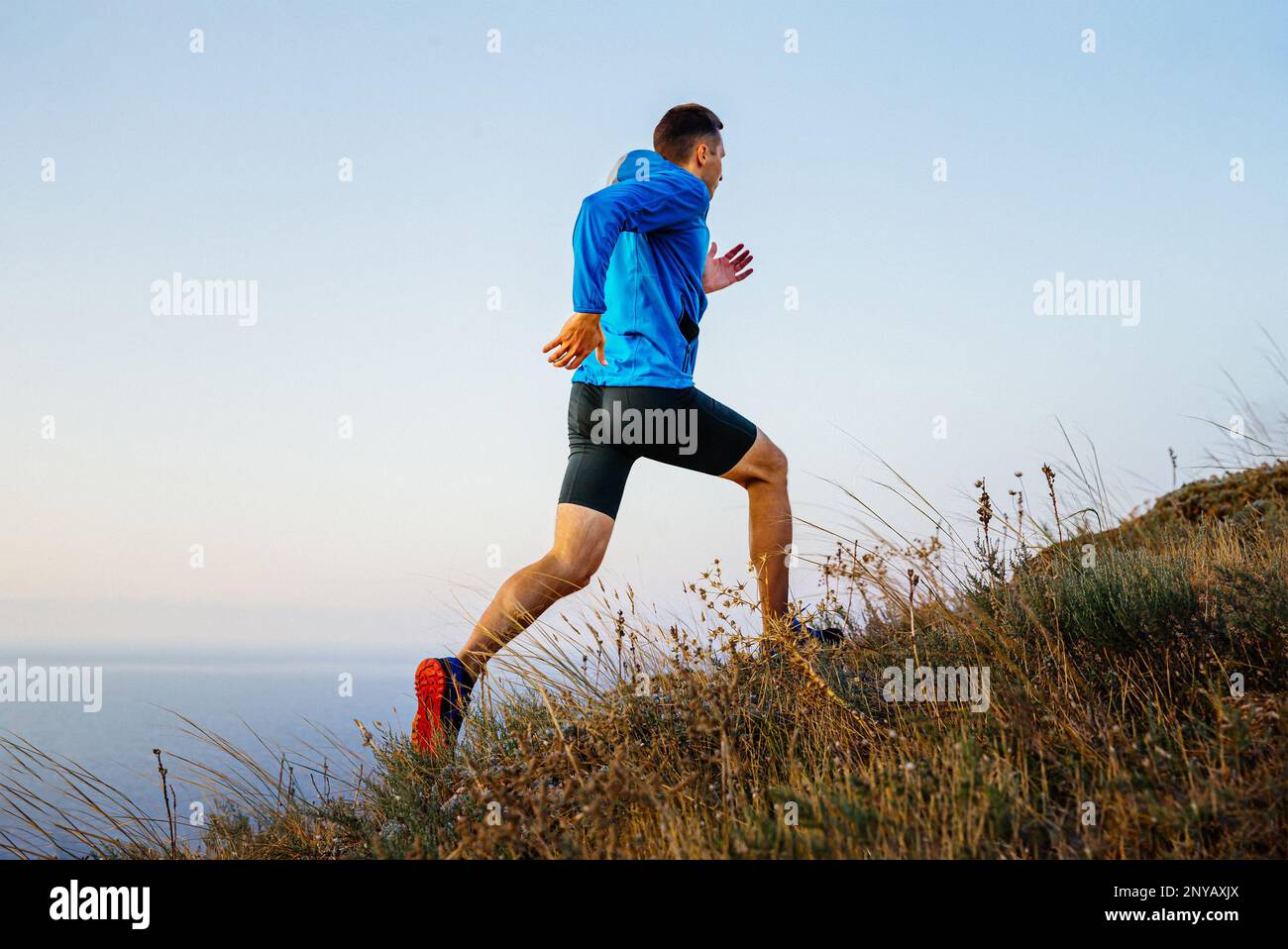 runner che corre sentiero di montagna in cielo e mare sullo sfondo Foto Stock