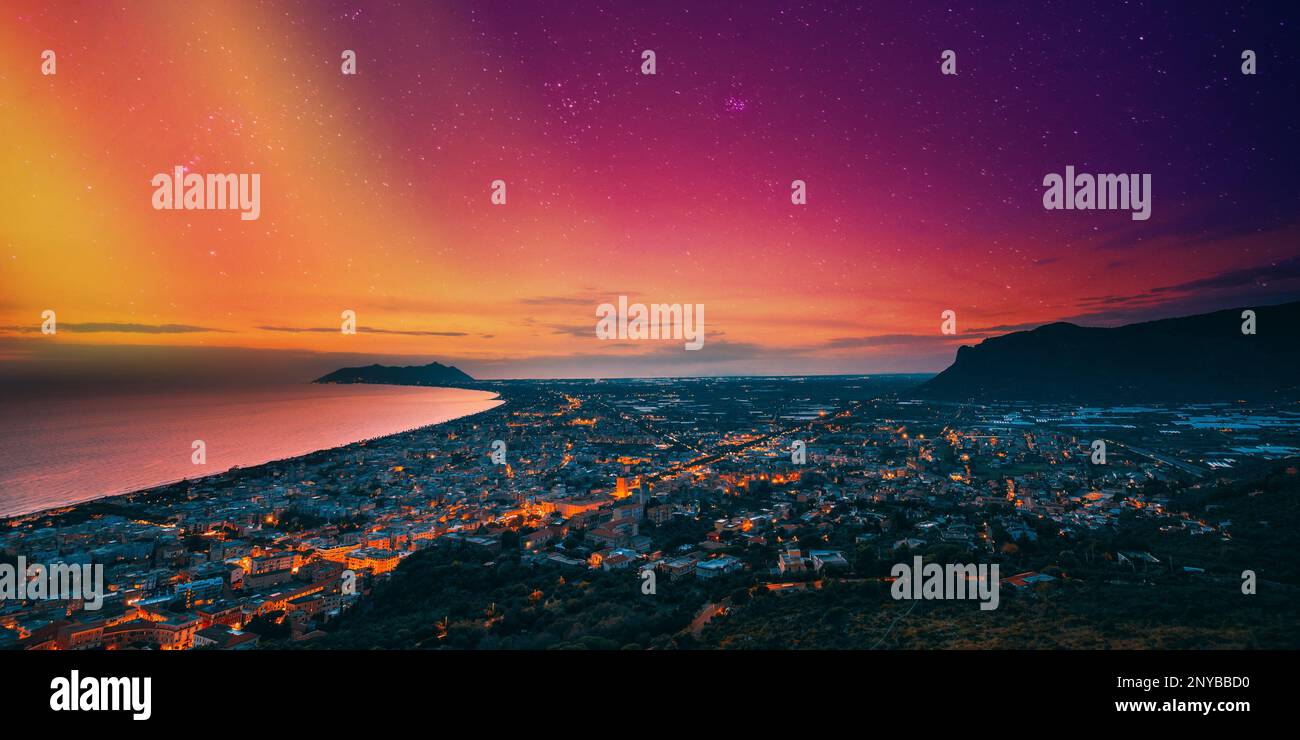 Terracina, Italia. Vista dall'alto skyline città al tramonto serale. Illuminazioni della città. Incredibile cielo del tramonto con luminoso cielo notturno saturo e colorato. Foto Stock