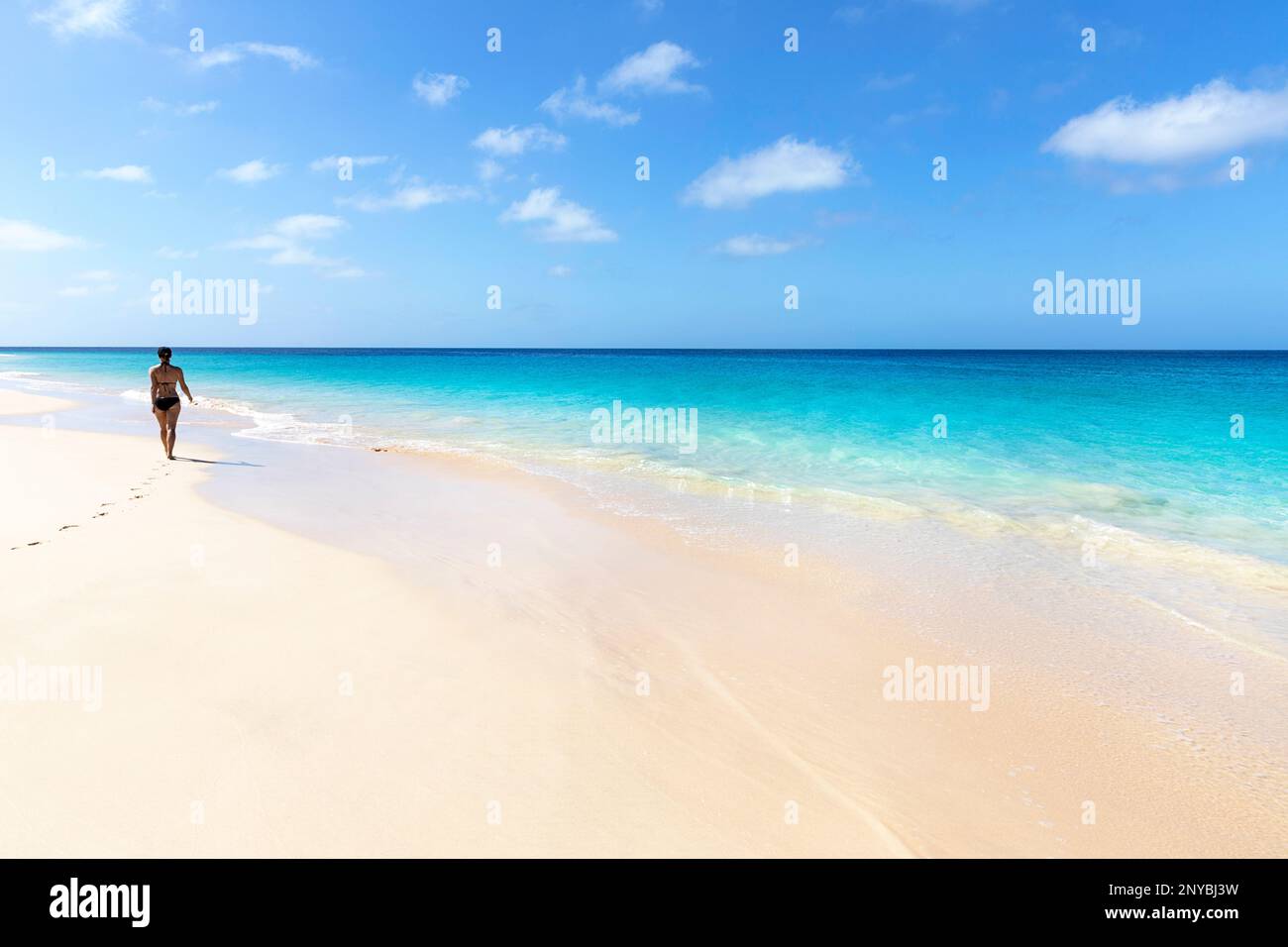 Donna turistica in costume da bagno in una vacanza a piedi su una spiaggia di sabbia idilliaca in una giornata di sole estate sull'isola di SAL, Cabo Verde Foto Stock