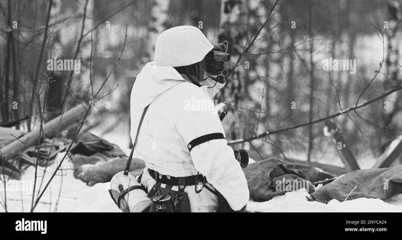 Scatti multipli. Uomo vestito come soldati tedeschi di fanteria Wehrmacht nella seconda guerra mondiale Nascosto seduta con arma in un Ambush e guardando il vecchio esercito Foto Stock
