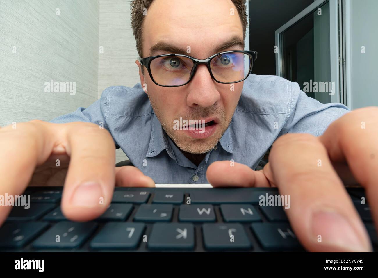 Uomo divertente e pazzo che usa un computer su sfondo bianco. le mani dell'uomo sulla tastiera Foto Stock