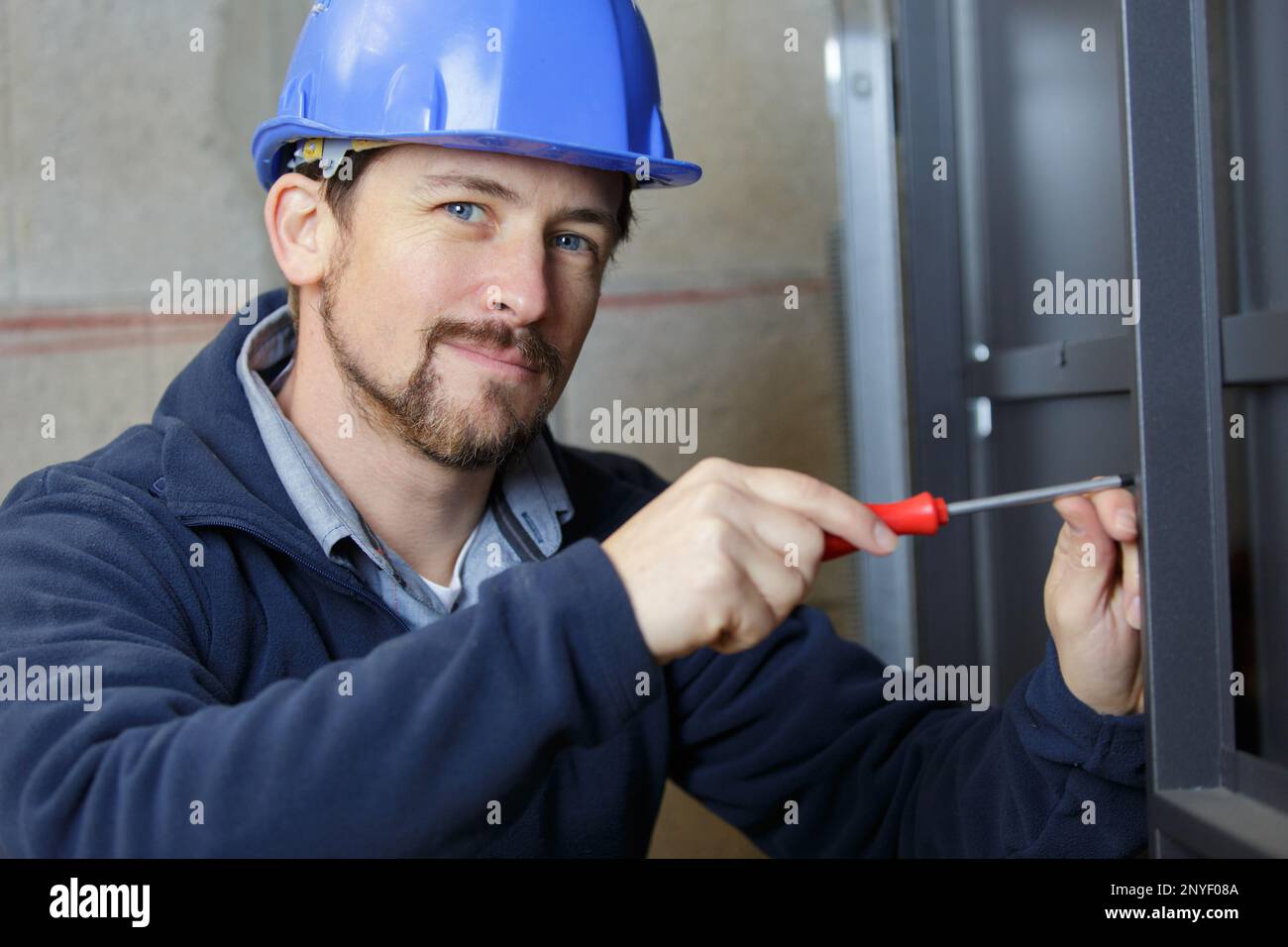 un giovane uomo avvita un cacciavite nel telaio Foto Stock