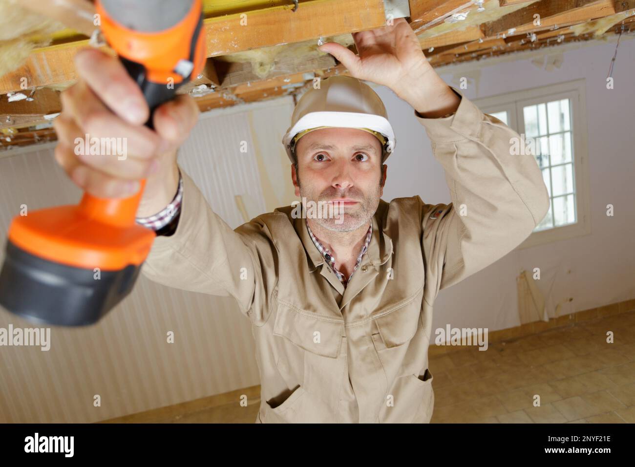 costruttore maschio che utilizza un trapano a batteria in testa Foto Stock