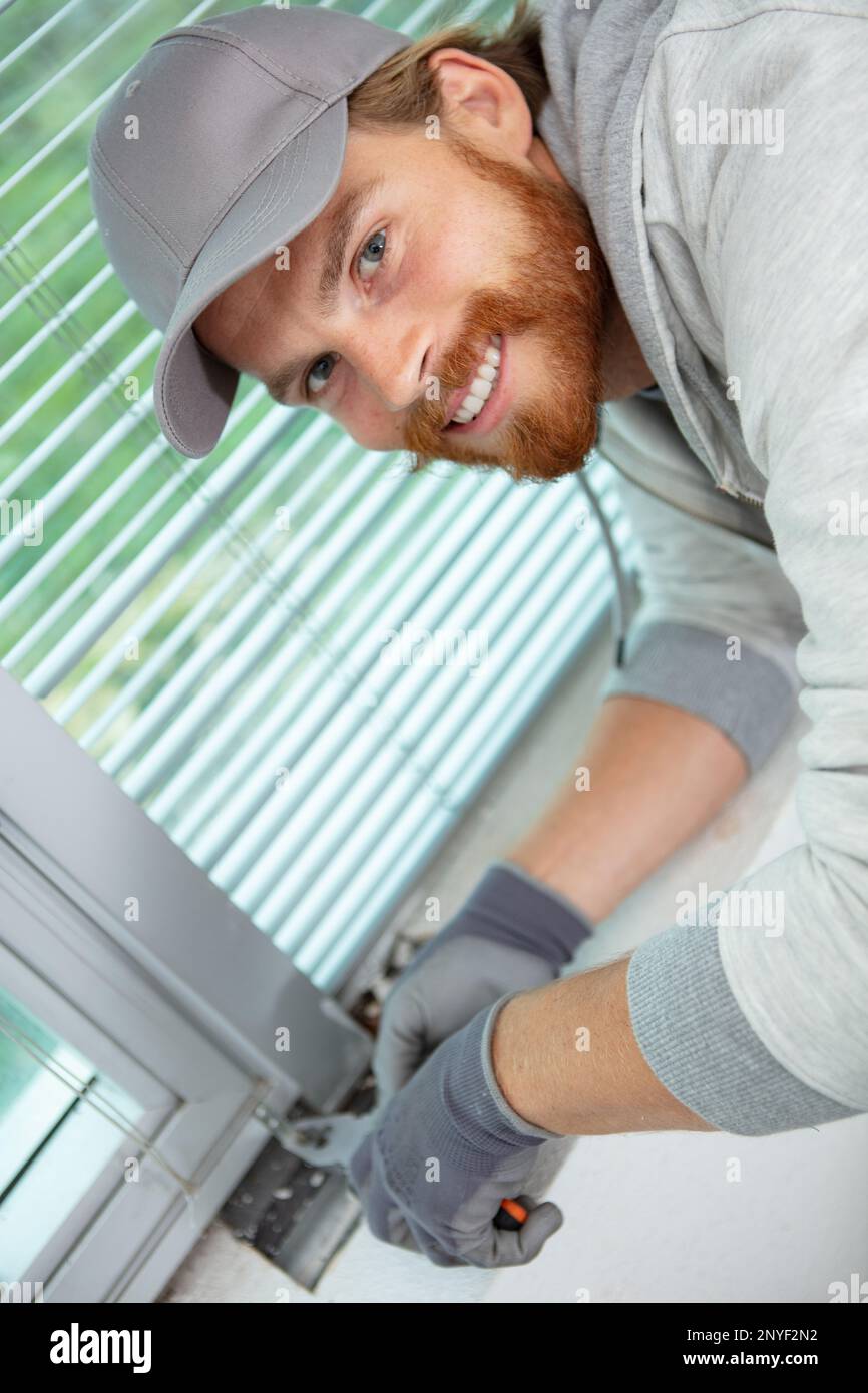 handyman regola la finestra con una pinza Foto Stock