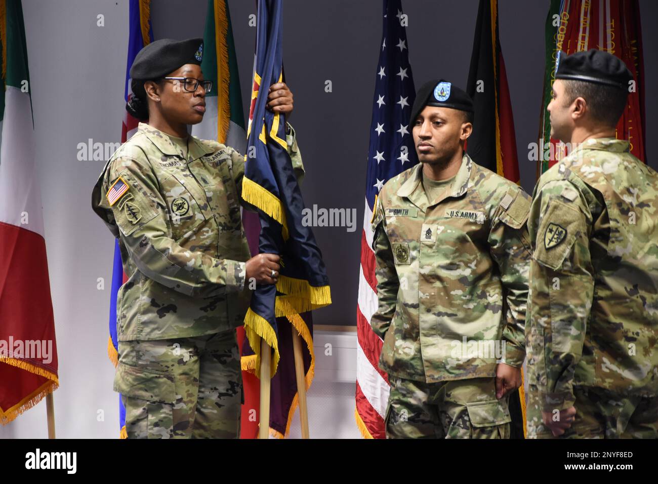 Il comando Sgt. Maji. Kisha M. Thomas (a sinistra) riceve gli Stati Uniti Esercito NATO Brigata guidon da Colon. Troy V. Alexander (a destra) durante una cerimonia di assunzione di responsabilità a Sembach Kaserne. La SGT. Major Reginald Smith (centro) ha servito come ufficiale non incaricato della cerimonia. Foto Stock