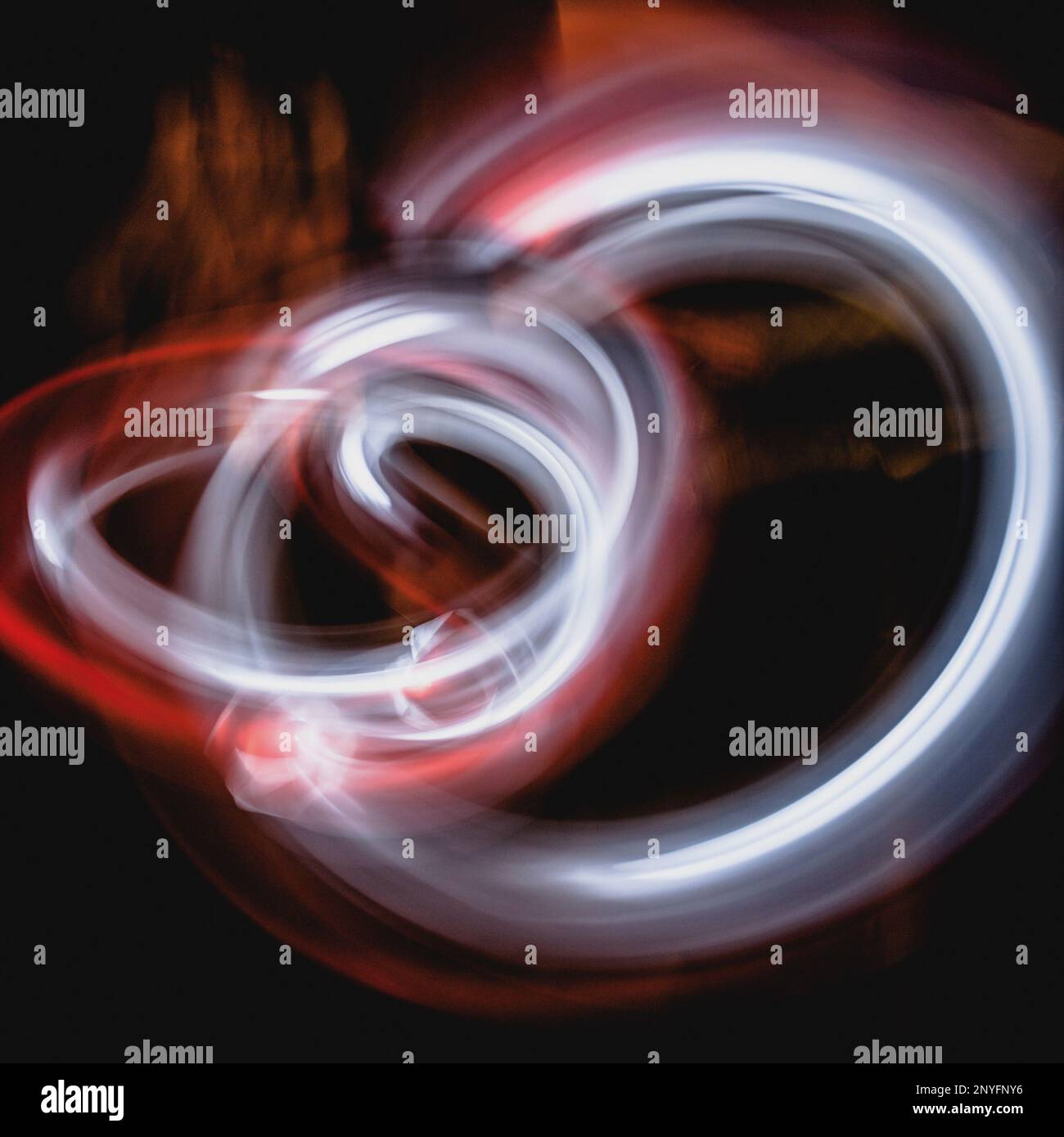 Sfondo astratto con tracce diffuse di rosso e bianco luminoso raggi su superfici scure e sfocate Foto Stock