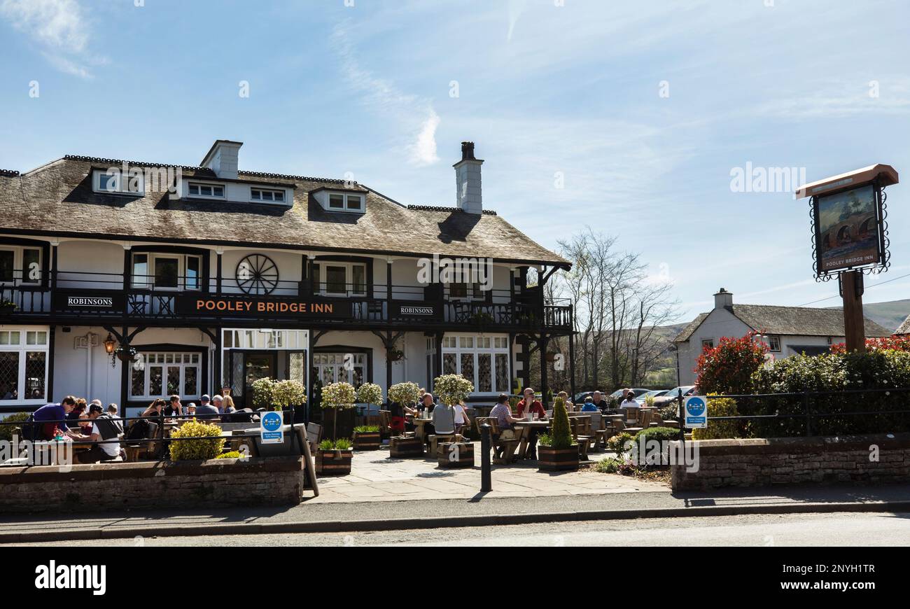 Un pub affollato chiamato Pooley Bridge Inn, dove i turisti mangiano fuori godendosi il sole al Pooley Bridge Ullswater Lake District, Cumbria Foto Stock