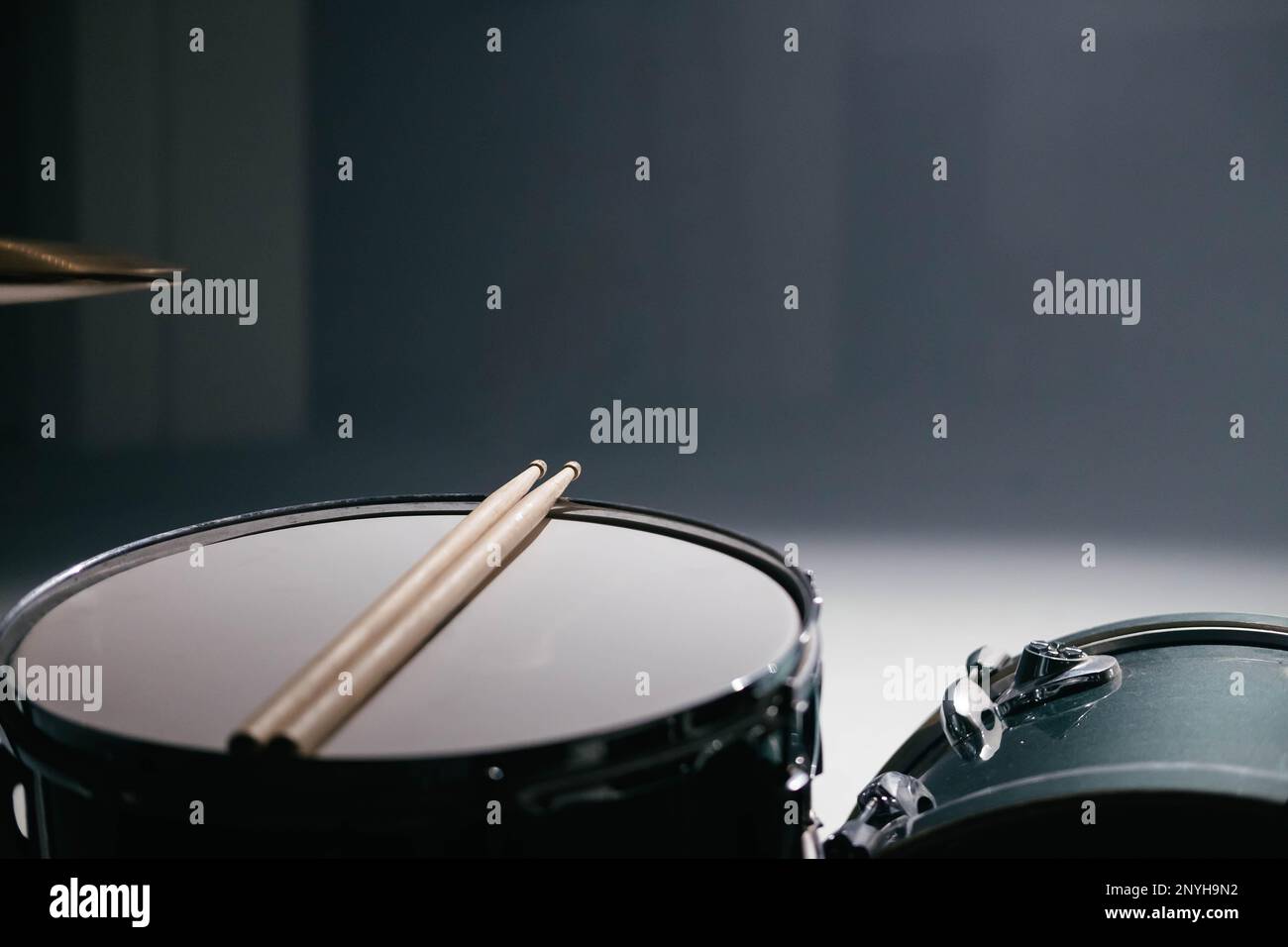 Un primo piano di un set di tamburi con bastoncini. Lo sfondo è scuro e c'è molto spazio per il testo. Foto Stock