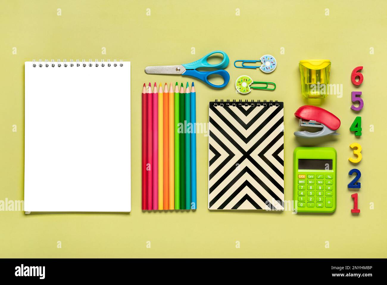Telaio da forniture scolastiche e d'ufficio clip di carta, penne, calcolatrice, affilatrice, blocco note, Pinzatrice isolata su sfondo verde Flat Lay Vista dall'alto Indietro t Foto Stock