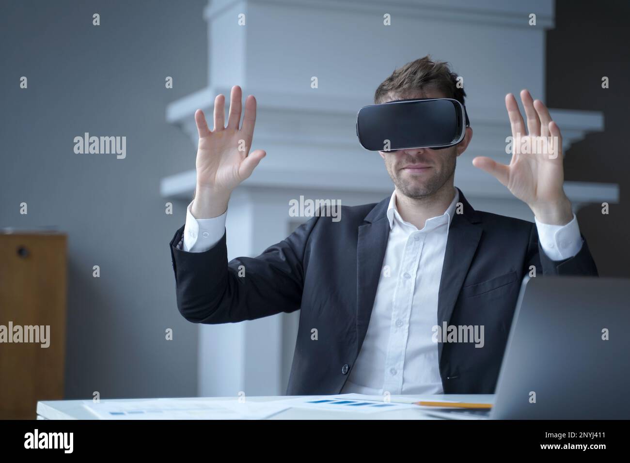 Uomo d'affari che utilizza la tecnologia della realtà aumentata nel lavoro da casa. Uomo CEO in realtà virtuale occhiali con le mani in alto in aria. Imprenditore focalizzato i Foto Stock