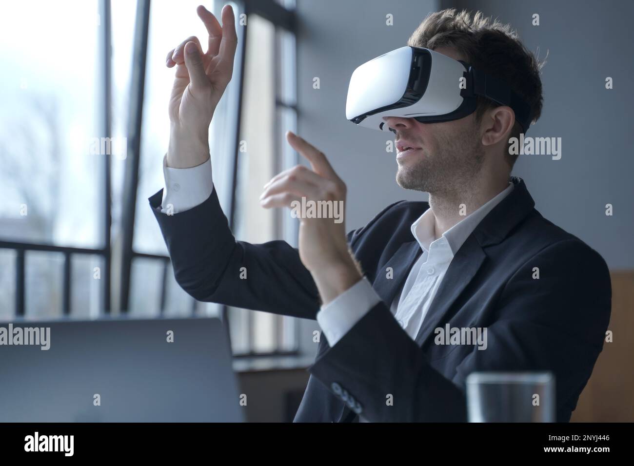 Il cyberspazio negli affari. Un uomo d'ufficio entusiasta che indossa occhiali vr che toccano oggetti con le mani nel mondo digitale, un uomo d'affari stupito in 3D occhiali Foto Stock