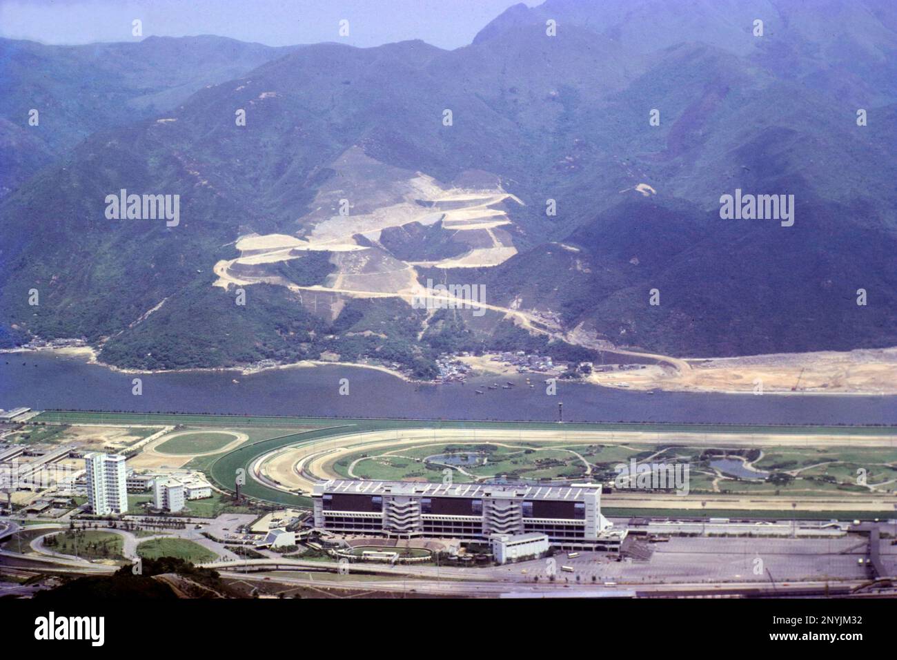 Vista paesaggistica della Grandstand all'Ippodromo di Shatin, da Kau a Shan, Shatin, New Territories, Hong Kong, nel 1980. Il fiume Shing Mun e le pendici inferiori di ma on Shan (ora ma on Shan New Town) alle spalle. Foto Stock