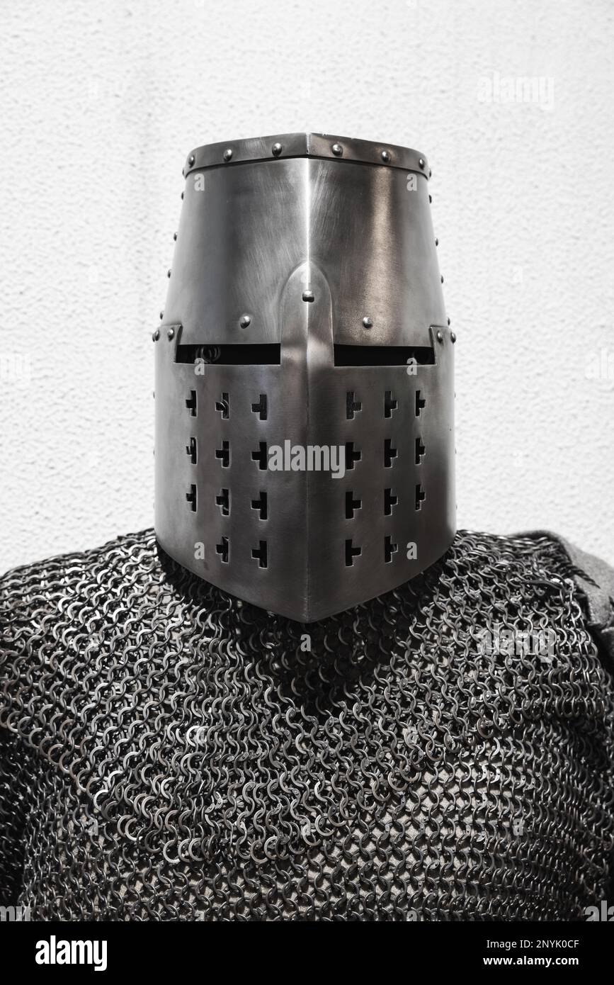 Armatura del cavaliere crociato medievale, casco in ferro chiuso e posta a catena, vista frontale davanti alla parete bianca Foto Stock